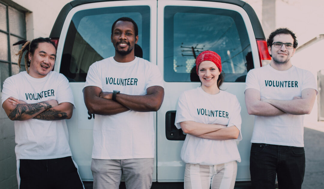 four individuals with white T-shirts with volunteer text